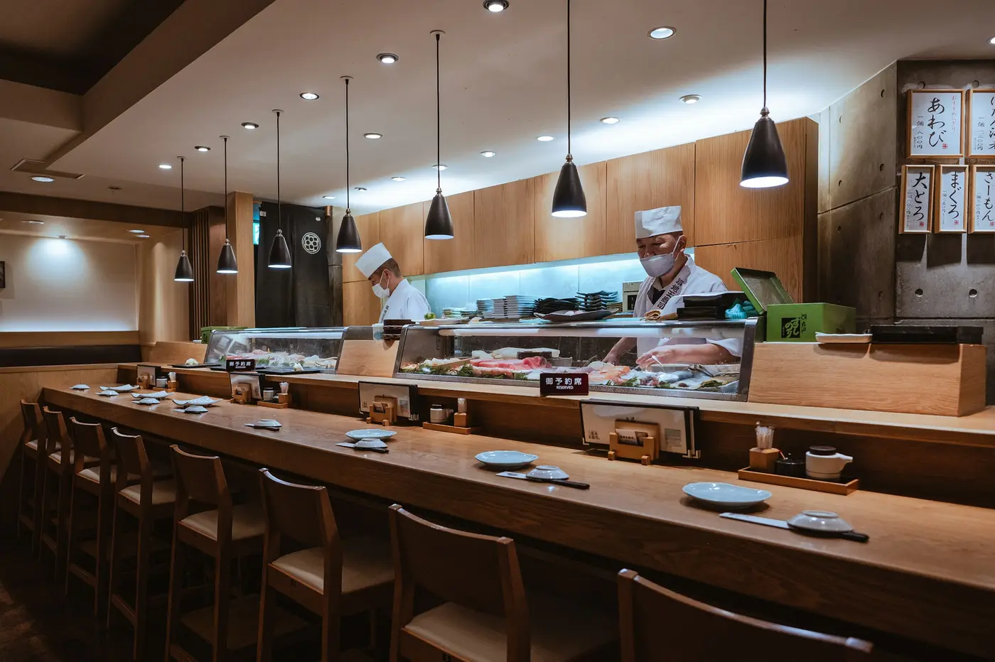 A long, pale wooden sushi counter in Ginza with the chef behind it