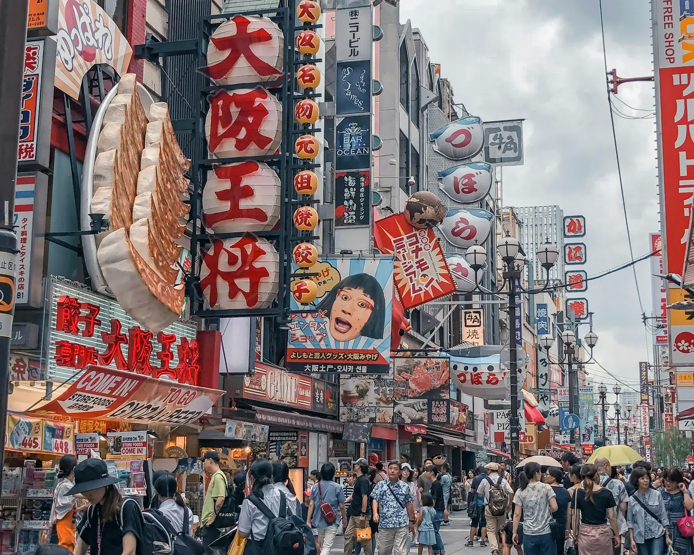 Crowds under the giant restaurant signs of Dotonbori in Osaka