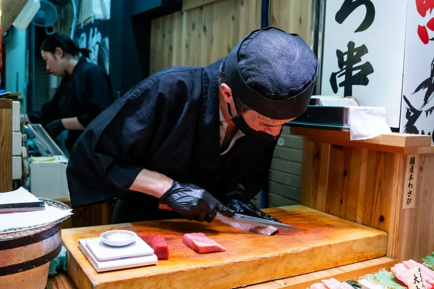 A sushi chef slicing fresh tuna on a wooden board