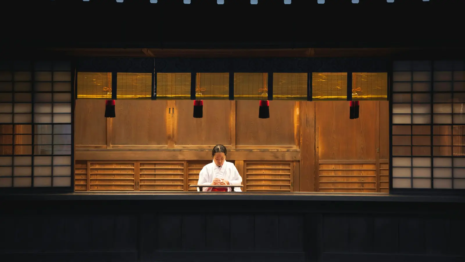 A chef waiting alone behind a long, empty wooden counter